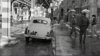 Movie still from “Blackboard Jungle” (1955), directed by Richard Brooks – An old car parked on the side of the street; Wide shot, High angle
