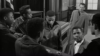 Movie still from “Blackboard Jungle” (1955), directed by Richard Brooks – A group of young men standing next to each other in a room; Medium shot, Over the shoulder angle