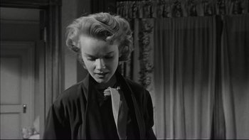 Movie still from “Blackboard Jungle” (1955), directed by Richard Brooks – A young woman with blonde ringlet hair wearing a black shirt and a tie; Close Up shot, Low angle