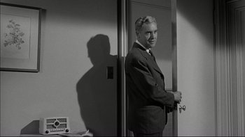 Movie still from “Blackboard Jungle” (1955), directed by Richard Brooks – A black and white photo of a man in a suit and tie; Medium shot, Over the shoulder angle