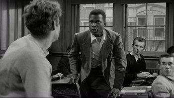 Movie still from “Blackboard Jungle” (1955), directed by Richard Brooks – A black and white photo of a man in a suit; Medium shot, Over the shoulder angle