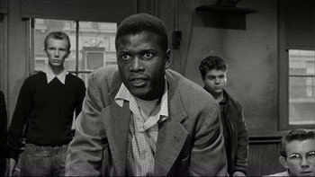 Movie still from “Blackboard Jungle” (1955), directed by Richard Brooks – A black and white photo of a man in a suit; Medium shot, Low angle