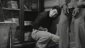 Movie still from “Blackboard Jungle” (1955), directed by Richard Brooks – A man leaning against a shelf in a room; Medium shot, Low angle