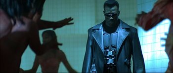 Movie still from “Blade” (1998), directed by Stephen Norrington – A man in a leather jacket standing in front of another man; Medium shot, Low angle