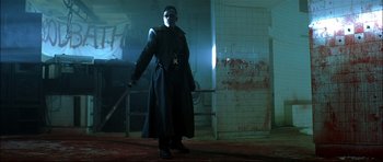 Movie still from “Blade” (1998), directed by Stephen Norrington – A man in a trench coat holding a sword; Wide shot, Low angle