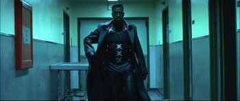Movie still from “Blade” (1998), directed by Stephen Norrington – A man in a black leather outfit and a black coat; Medium shot, Low angle
