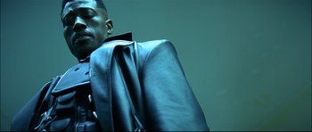 Movie still from “Blade” (1998), directed by Stephen Norrington – A man in a black jacket is sitting down; Close Up shot, Low angle