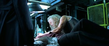 Movie still from “Blade” (1998), directed by Stephen Norrington – A man with long white hair is sitting on a couch and looking at a laptop; Medium shot, Low angle
