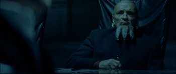 Movie still from “Blade” (1998), directed by Stephen Norrington – An older man sitting at a table in a dark room; Close Up shot, Over the shoulder angle