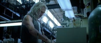 Movie still from “Blade” (1998), directed by Stephen Norrington – A man with long white hair working in a lab; Medium shot, Low angle