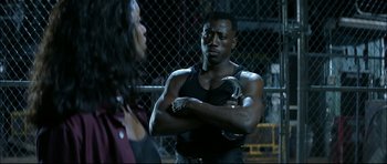 Movie still from “Blade” (1998), directed by Stephen Norrington – A man and a woman standing next to each other in front of a chain link fence; Medium shot, Over the shoulder angle