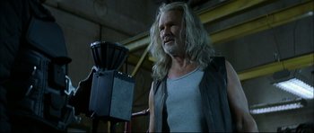 Movie still from “Blade” (1998), directed by Stephen Norrington – A man with long white hair is standing next to a machine; Medium shot, Low angle