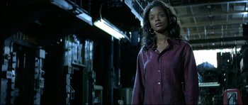 Movie still from “Blade” (1998), directed by Stephen Norrington – A woman standing in the dark wearing a purple shirt; Medium shot, Low angle