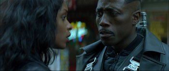 Movie still from “Blade” (1998), directed by Stephen Norrington – A man and a woman standing next to each other on the street; Close Up shot, Over the shoulder angle