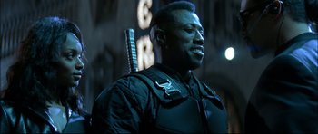 Movie still from “Blade” (1998), directed by Stephen Norrington – A man in a black jacket with a guitar in his hand; Close Up shot, Low angle