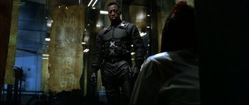 Movie still from “Blade” (1998), directed by Stephen Norrington – A man in a black outfit standing next to a building; Medium shot, Low angle