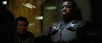 Movie still from “Blade” (1998), directed by Stephen Norrington – A man in a black jacket is looking at the camera; Close Up shot, Low angle