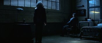 Movie still from “Blade” (1998), directed by Stephen Norrington – Two people are sitting in a dark room; Wide shot, Over the shoulder angle