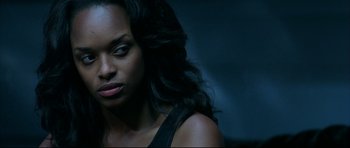 Movie still from “Blade” (1998), directed by Stephen Norrington – A woman with long black curly hair looking to her left; Close Up shot, Over the shoulder angle