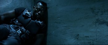 Movie still from “Blade” (1998), directed by Stephen Norrington – A man leaning up against a wall in a dark room; Close Up shot, High angle