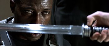 Movie still from “Blade” (1998), directed by Stephen Norrington – A person holding a sword; Close Up shot, Low angle