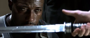 Movie still from “Blade” (1998), directed by Stephen Norrington – A person holding a sword; Close Up shot, Low angle