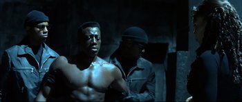 Movie still from “Blade” (1998), directed by Stephen Norrington – A man standing next to another man in a dark room; Close Up shot, Low angle