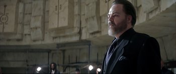 Movie still from “Blade” (1998), directed by Stephen Norrington – A man in a suit and tie standing next to a wall; Medium shot, Low angle