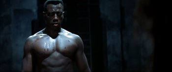 Movie still from “Blade” (1998), directed by Stephen Norrington – A man with no shirt is standing in a dark room; Close Up shot, Low angle