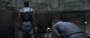 Movie still from “Blade” (1998), directed by Stephen Norrington – A man with a sword in his hand standing next to another man; Medium shot, Over the shoulder angle