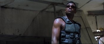Movie still from “Blade” (1998), directed by Stephen Norrington – A man in a leather vest is looking at the camera; Close Up shot, Low angle