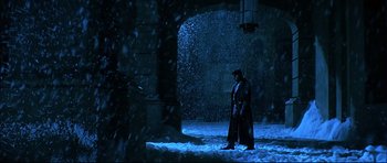Movie still from “Blade” (1998), directed by Stephen Norrington – A man in a long black coat standing in the snow; Wide shot, Low angle