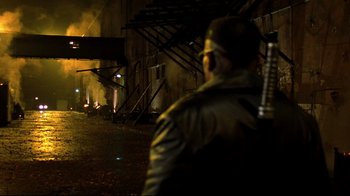 Movie still from “Blade II” (2002), directed by Guillermo del Toro – A man with a gun standing in front of a fire; Wide shot, Over the shoulder angle