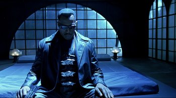 Movie still from “Blade II” (2002), directed by Guillermo del Toro – A man sitting on top of a bed wearing a leather jacket; Medium shot, High angle