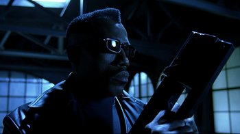 Movie still from “Blade II” (2002), directed by Guillermo del Toro – A man with glasses is looking at his cell phone; Close Up shot, Low angle