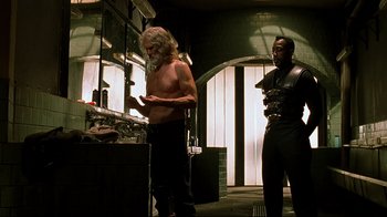 Movie still from “Blade II” (2002), directed by Guillermo del Toro – A man with long white hair and no shirt standing next to another man; Medium shot, Low angle