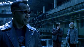 Movie still from “Blade II” (2002), directed by Guillermo del Toro – A man in sunglasses and a jacket standing next to another man; Close Up shot, Over the shoulder angle