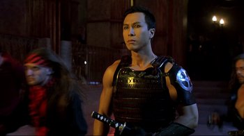 Movie still from “Blade II” (2002), directed by Guillermo del Toro – A man in a leather vest holding a sword; Medium shot, Over the shoulder angle