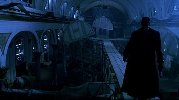Movie still from “Blade II” (2002), directed by Guillermo del Toro – A man standing in a dark room next to scaffolding; Wide shot, Low angle