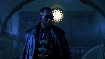 Movie still from “Blade II” (2002), directed by Guillermo del Toro – A man wearing sunglasses and a leather jacket in front of a clock; Close Up shot, Low angle