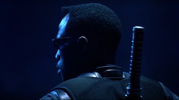 Movie still from “Blade II” (2002), directed by Guillermo del Toro – A person wearing glasses and holding a sword; Close Up shot, Low angle