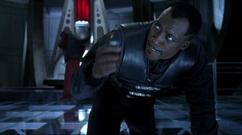 Movie still from “Blade II” (2002), directed by Guillermo del Toro – A man holding a cell phone while standing in a room; Close Up shot, High angle