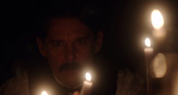 Movie still from “Tesla” (2020), directed by Michael Almereyda – A man is holding a candle in the dark; Close Up shot, Low angle