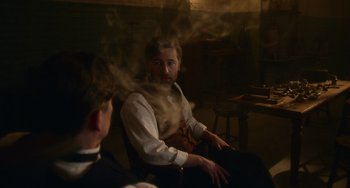 Movie still from “Tesla” (2020), directed by Michael Almereyda – A man sitting in front of another man with steam coming out of his mouth; Medium shot, Over the shoulder angle