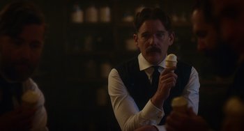 Movie still from “Tesla” (2020), directed by Michael Almereyda – A man in a white dress shirt and tie holding an ice cream cone; Close Up shot, Over the shoulder angle