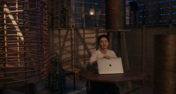 Movie still from “Tesla” (2020), directed by Michael Almereyda – A person sitting at a table with a laptop; Wide shot, High angle