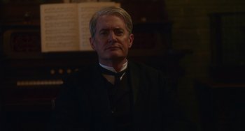 Movie still from “Tesla” (2020), directed by Michael Almereyda – An older man wearing a suit and tie; Medium shot, Low angle