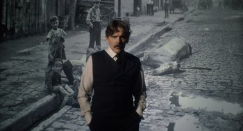 Movie still from “Tesla” (2020), directed by Michael Almereyda – A man standing in front of an old photo; Medium shot, Low angle