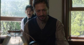 Movie still from “Tesla” (2020), directed by Michael Almereyda – A man in a suit and tie next to another man in a suit and tie; Medium shot, Over the shoulder angle