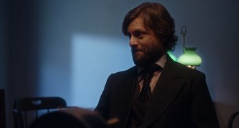 Movie still from “Tesla” (2020), directed by Michael Almereyda – A man with a beard and a suit and tie; Close Up shot, Over the shoulder angle